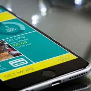 Close-up of a smartphone displaying a billing app interface on a reflective surface.