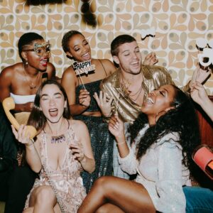 A diverse group of friends joyfully celebrating New Year's Eve indoors, capturing festive fun.
